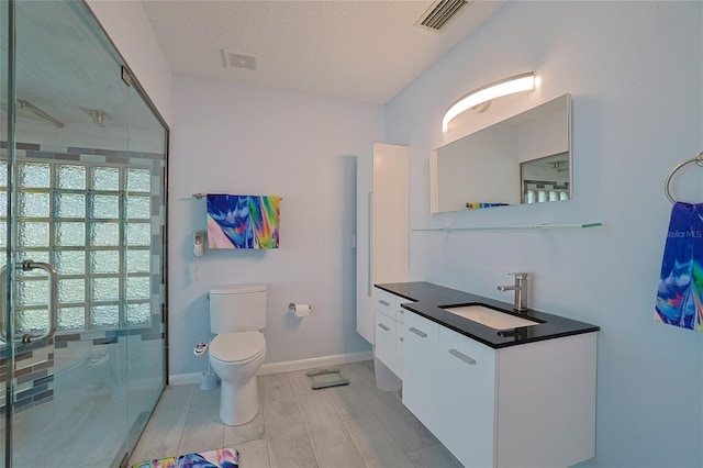 bathroom featuring vanity, an enclosed shower, a textured ceiling, and toilet