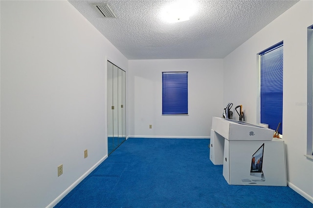 interior space with a textured ceiling and dark carpet