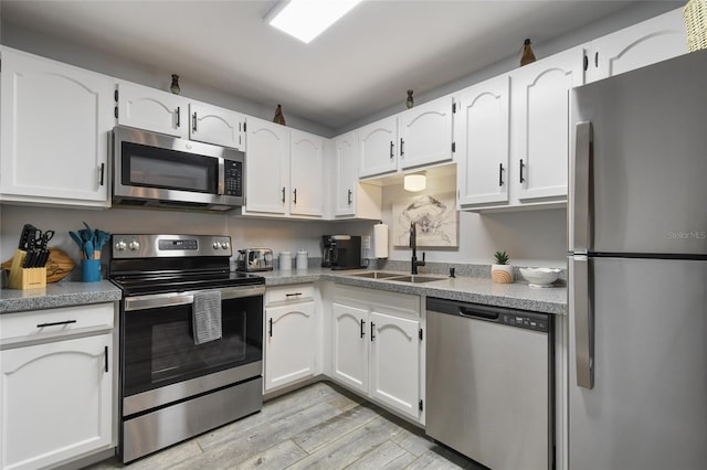 kitchen featuring sink, stainless steel appliances, light hardwood / wood-style floors, and white cabinetry