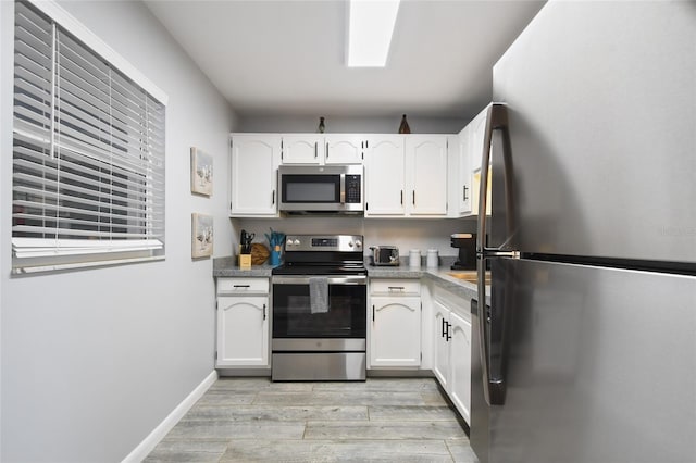 kitchen featuring appliances with stainless steel finishes, white cabinetry, and light wood-type flooring