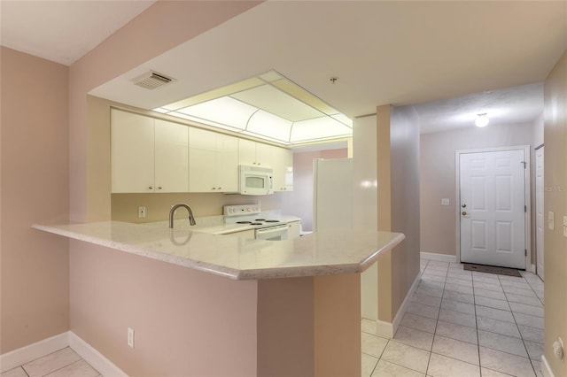 kitchen with visible vents, white cabinetry, white appliances, a peninsula, and baseboards