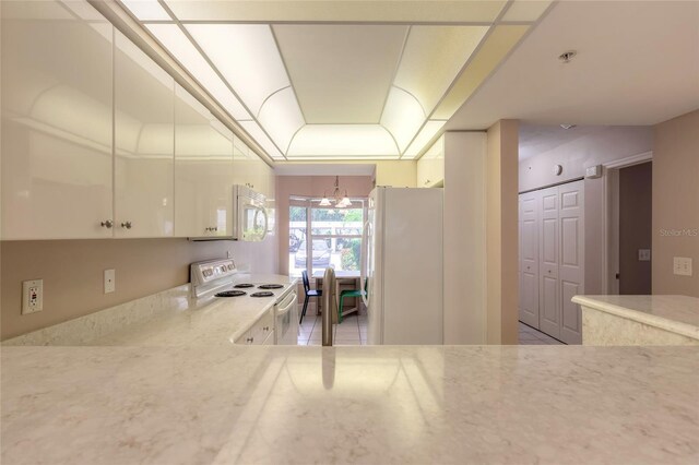 kitchen with white cabinetry, a notable chandelier, white appliances, light tile patterned floors, and light stone counters