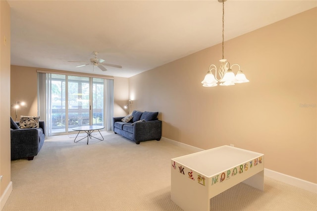 living room featuring baseboards, ceiling fan with notable chandelier, and light colored carpet