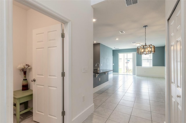 corridor featuring a notable chandelier and light tile patterned floors