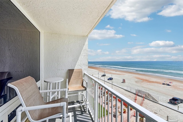 balcony featuring a view of the beach and a water view