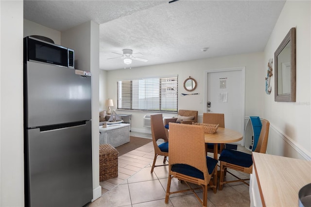 dining space with ceiling fan, light tile patterned floors, and a textured ceiling