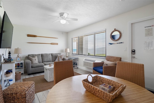 living room with a textured ceiling, ceiling fan, and light hardwood / wood-style floors