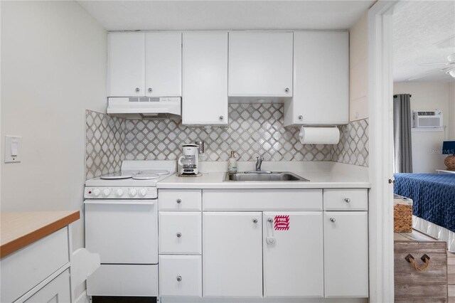 kitchen with sink, white stove, backsplash, and white cabinets