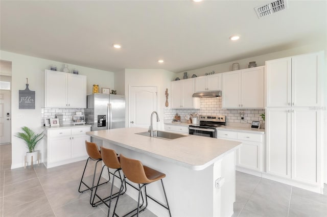 kitchen featuring a kitchen island with sink, stainless steel appliances, and white cabinetry