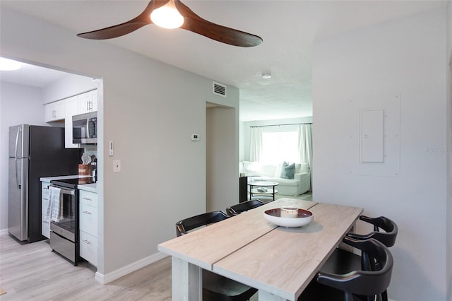 dining area with ceiling fan, light hardwood / wood-style flooring, and electric panel