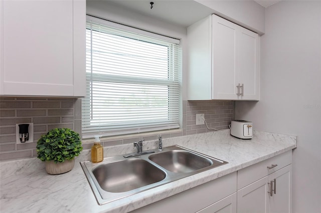 kitchen with white cabinets, tasteful backsplash, sink, and light stone counters