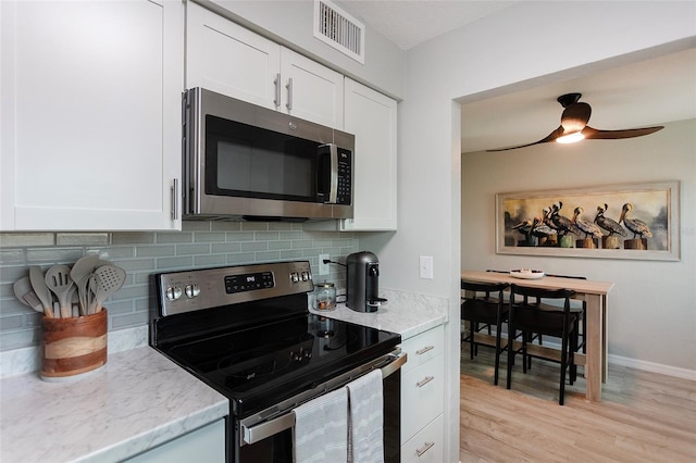 kitchen with appliances with stainless steel finishes, ceiling fan, light hardwood / wood-style floors, and white cabinets