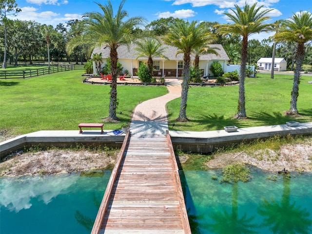 dock area featuring a lawn, a water view, and fence