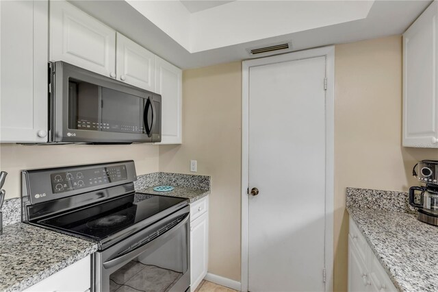 kitchen featuring white cabinets, black range with electric cooktop, and light stone countertops