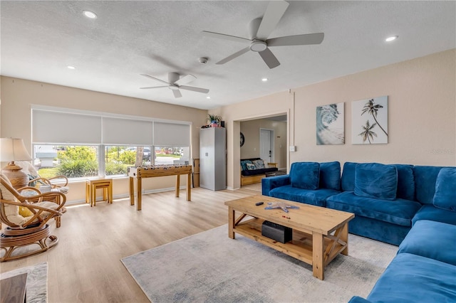 living room with a textured ceiling, light hardwood / wood-style floors, and ceiling fan