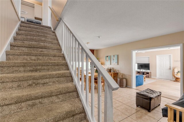 staircase featuring tile patterned flooring and a textured ceiling