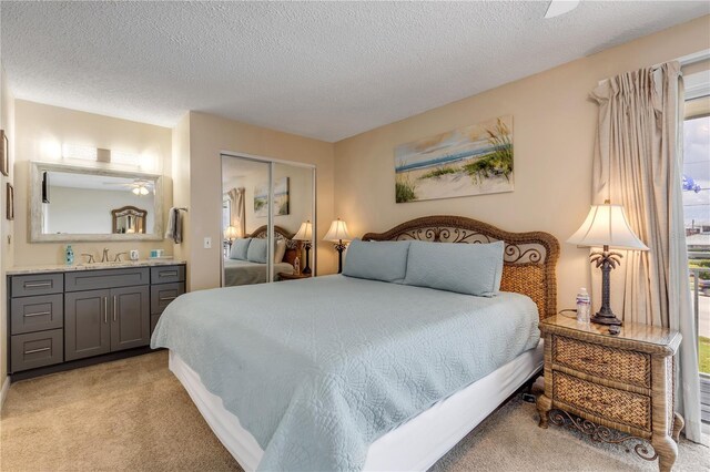 carpeted bedroom with ceiling fan, a textured ceiling, a closet, and sink