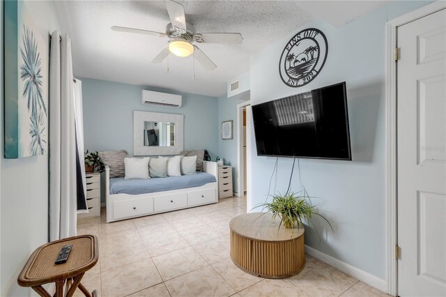 living room featuring a wall unit AC, ceiling fan, light tile patterned floors, and a textured ceiling