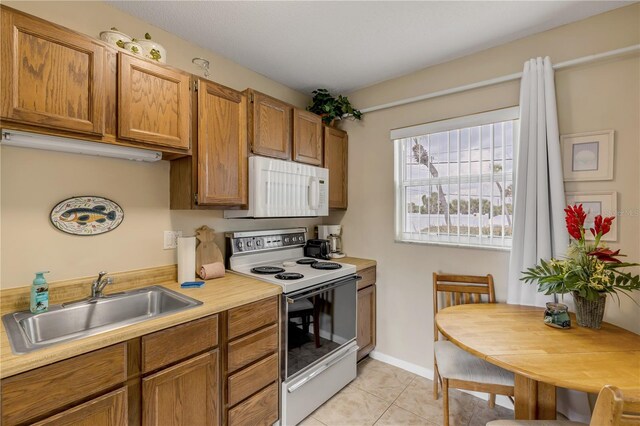 kitchen featuring sink, light tile patterned flooring, and white appliances