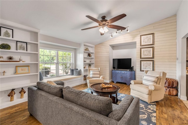 living room with lofted ceiling, wood walls, and wood finished floors