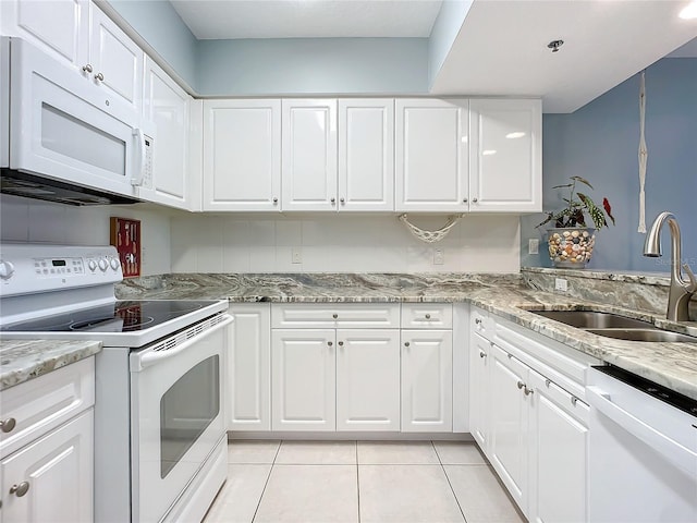 kitchen with white cabinetry, white appliances, light stone countertops, and sink