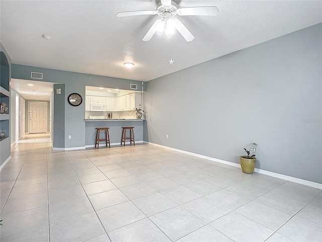 unfurnished living room with light tile patterned floors, a textured ceiling, and ceiling fan