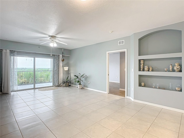 empty room featuring light tile patterned floors, built in features, a textured ceiling, and ceiling fan