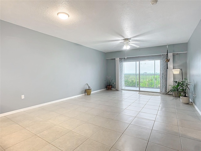 tiled spare room with a textured ceiling and ceiling fan