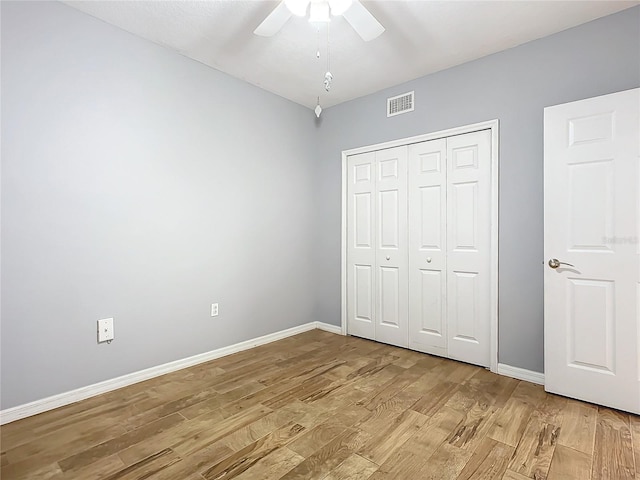 unfurnished bedroom featuring ceiling fan, light hardwood / wood-style floors, and a closet