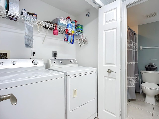 laundry room with washing machine and clothes dryer and light tile patterned floors