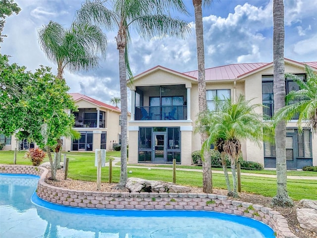 back of house with a yard, a sunroom, and a balcony