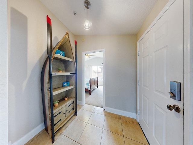 hallway featuring vaulted ceiling and light tile patterned floors