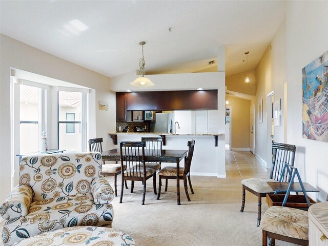 carpeted dining room featuring lofted ceiling and sink