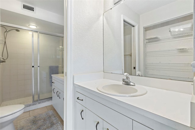 bathroom with a shower with shower door, tile patterned flooring, toilet, and vanity