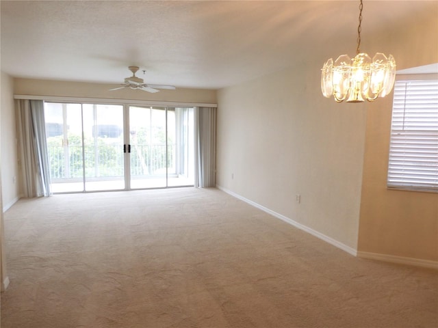 unfurnished room featuring ceiling fan with notable chandelier and carpet floors