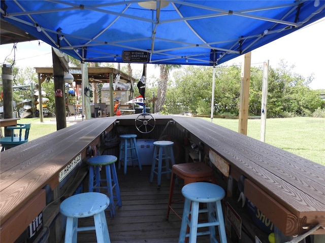 wooden terrace featuring exterior bar and a lawn