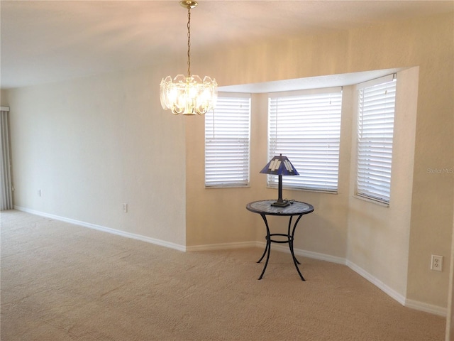 carpeted empty room with a notable chandelier