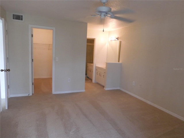 unfurnished bedroom with a closet, ceiling fan, light colored carpet, and a spacious closet