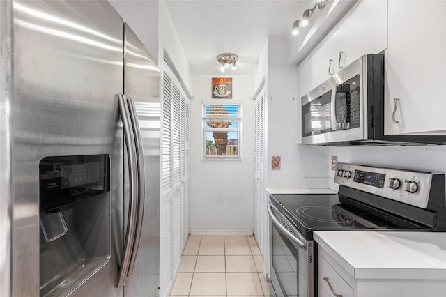 kitchen featuring light tile patterned floors, appliances with stainless steel finishes, and white cabinets