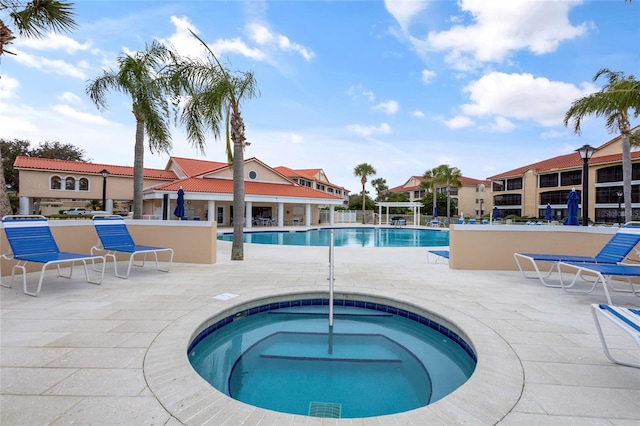 view of pool with a hot tub and a patio