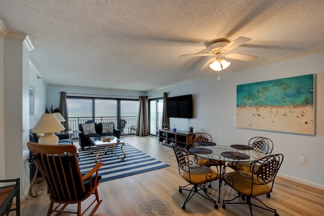 dining area with light wood-type flooring, ornamental molding, and ceiling fan