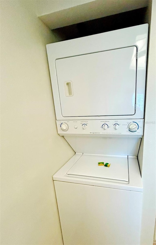 clothes washing area featuring stacked washer and clothes dryer