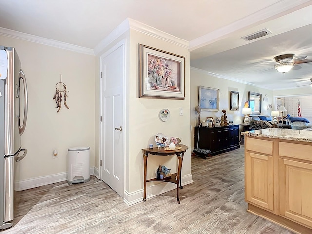 hallway featuring light wood-type flooring, visible vents, crown molding, and baseboards