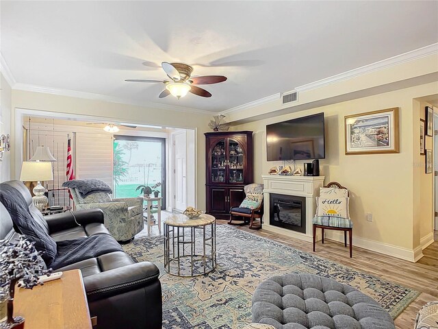 living room with ceiling fan, wood-type flooring, and crown molding