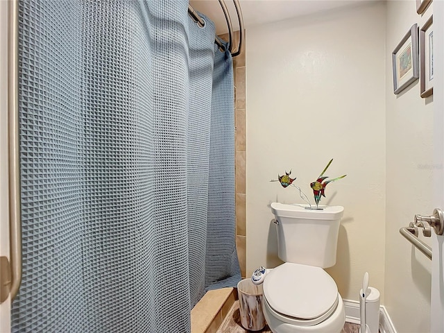 bathroom featuring curtained shower, baseboards, and toilet