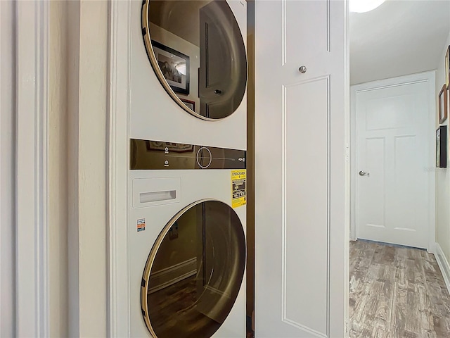 laundry room featuring laundry area, stacked washer and clothes dryer, and light wood-style floors