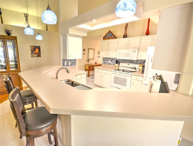 kitchen featuring kitchen peninsula, hanging light fixtures, sink, backsplash, and white appliances