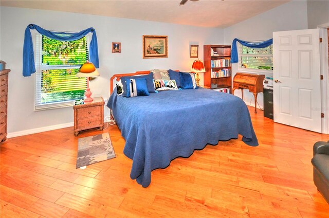 bedroom with multiple windows, vaulted ceiling, and hardwood / wood-style floors