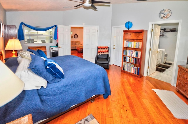 bedroom with hardwood / wood-style floors, ceiling fan, vaulted ceiling, and connected bathroom