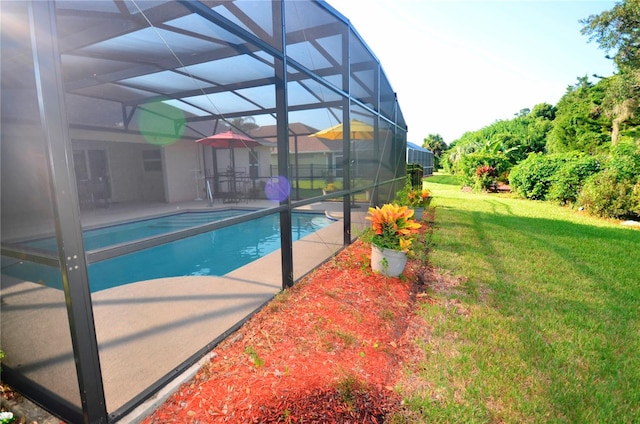 view of swimming pool with glass enclosure, a patio area, and a lawn